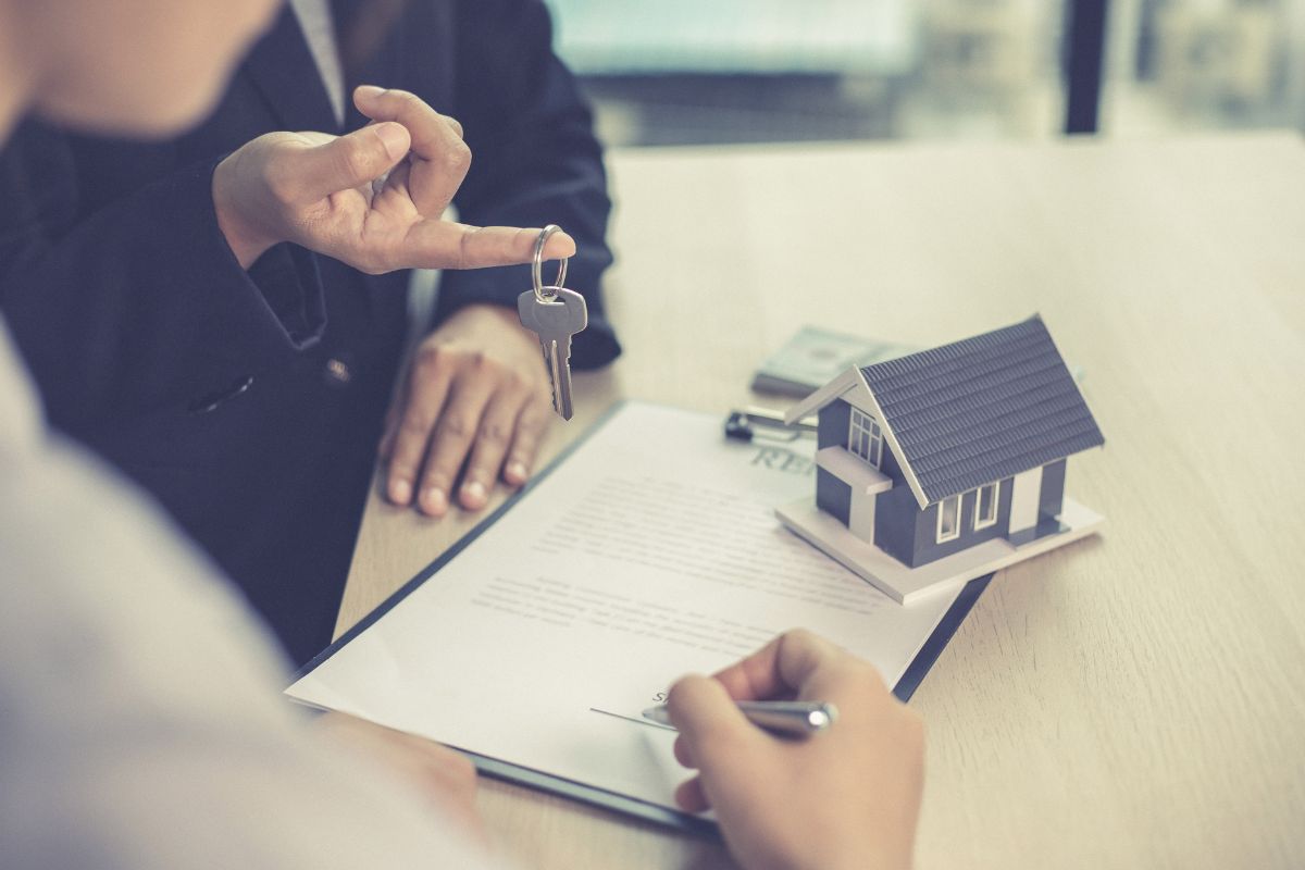 Persone che stipulano un contratto di affito e miniatura di una casa