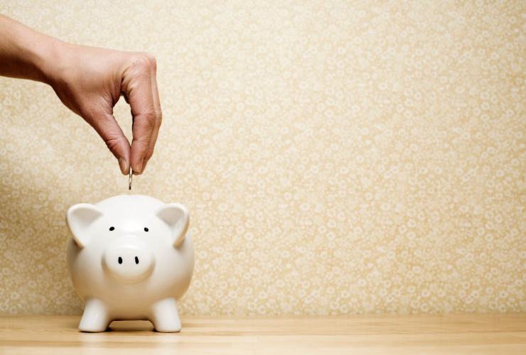Persona che mette una moneta nel salvadanaio