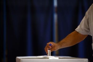 Persona che ha appena votato e inserisce il voto nell'urna elettorale
