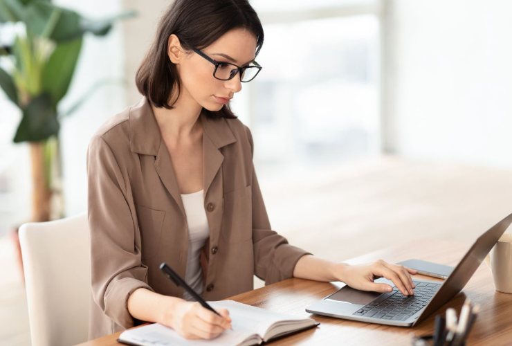 Persona che consulta il web e prende appunti