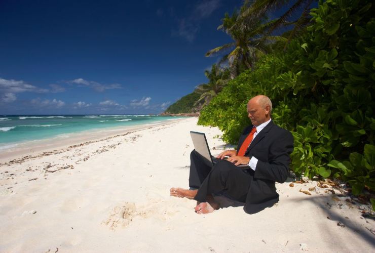 Persoa che lavora al computer in riva al mare