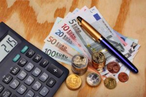 Calcolatrice, banconote, monete e penna