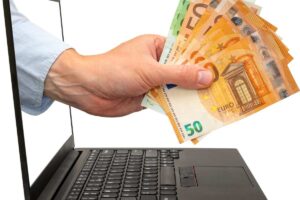 Mano con banconote che esce da un pc
