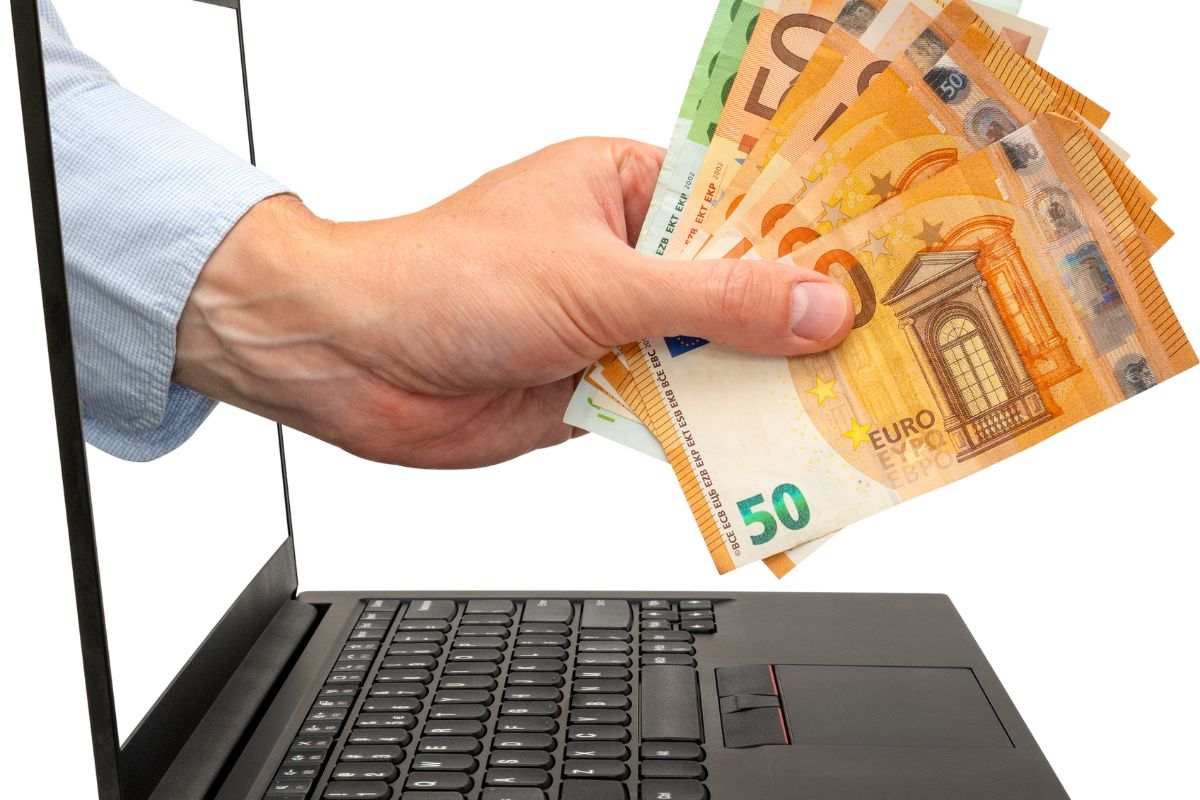 Mano con banconote che esce da un pc