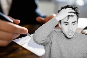 Uomo preoccupato e firma di un assegno