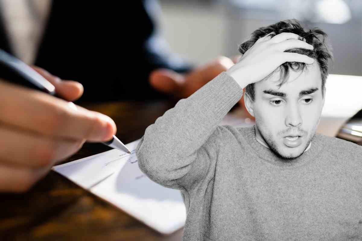 Uomo preoccupato e firma di un assegno