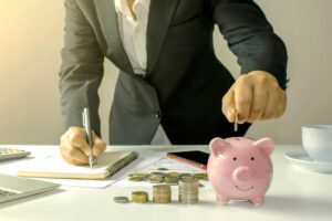 persona che fa calcoli e mette soldi in un salvadanaio