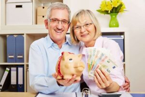 pensionati che hanno in mano un salvadanaio e banconote